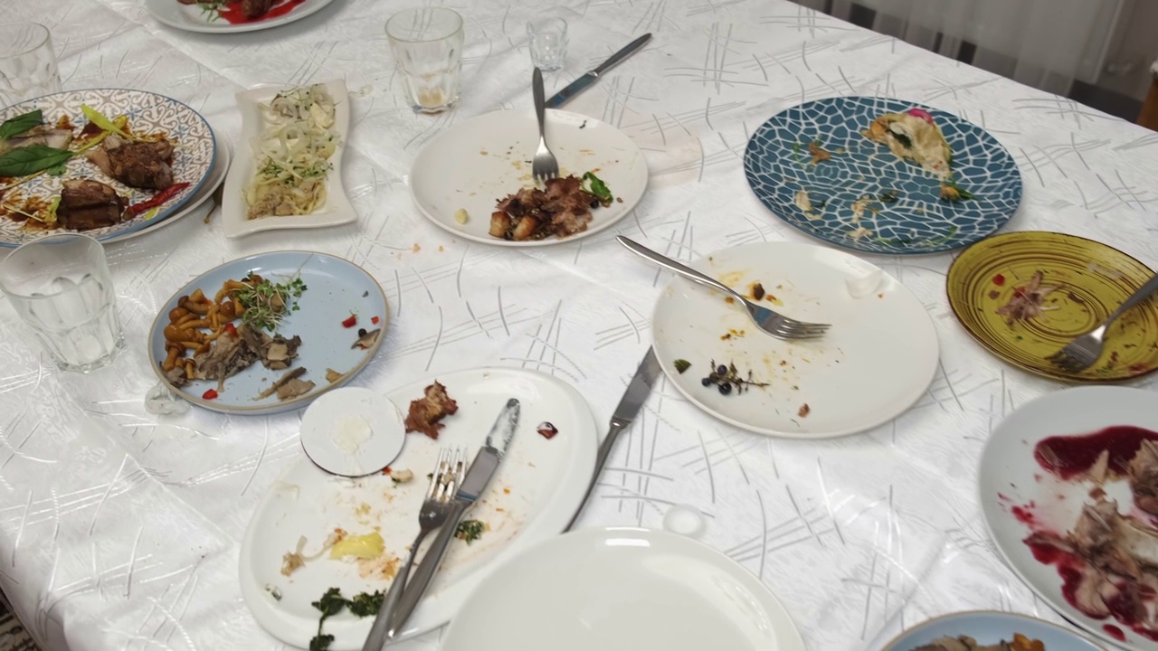 晚宴后餐桌上浪费的食物。桌子上有空盘子。相机jpgement。视频素材