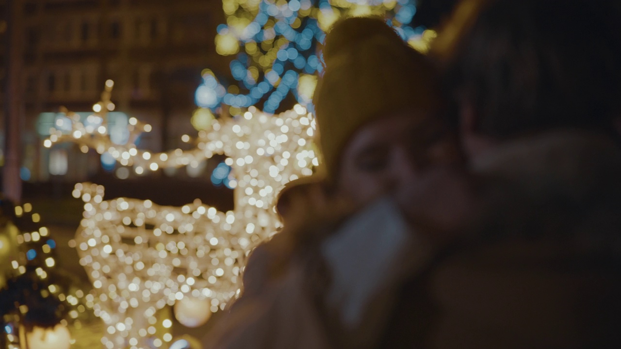 一名年轻女子在市中心广场拥抱她的男友，背景是圣诞树和彩灯视频素材