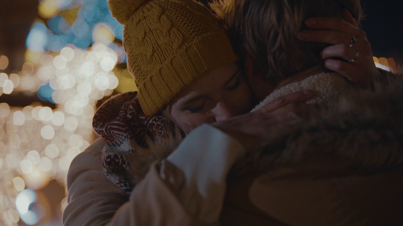 SLO MO夫妇在城市广场拥抱，背景是圣诞树和彩灯视频素材