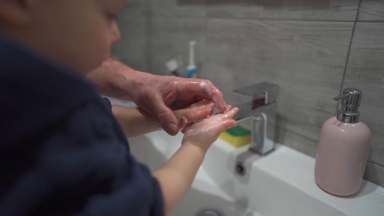 爷爷教小孙子洗手。那孩子在浴室的水槽上洗手。2019冠状病毒病期间的手卫生视频下载