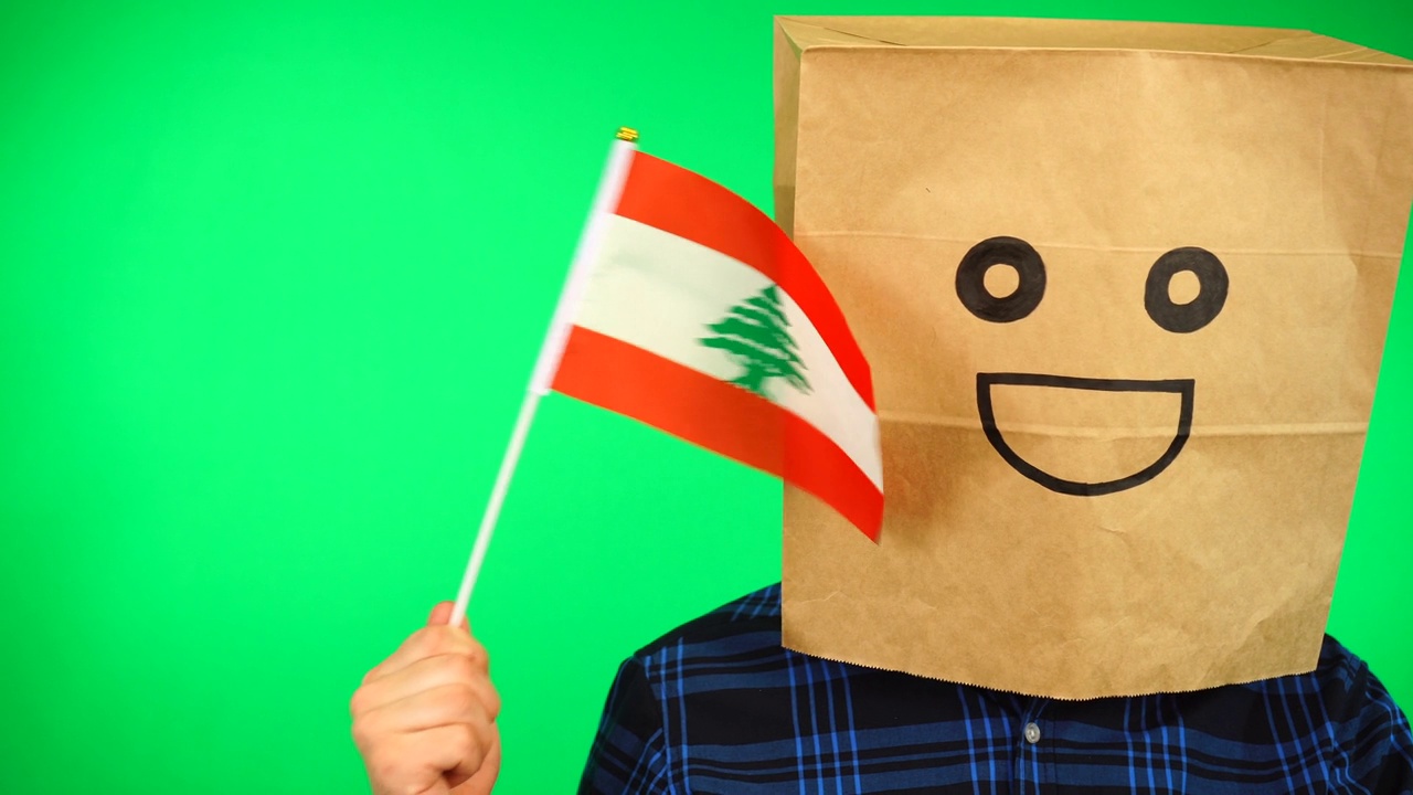 男人的肖像与纸袋在头上挥舞黎巴嫩国旗与微笑的脸在绿色的背景。视频下载