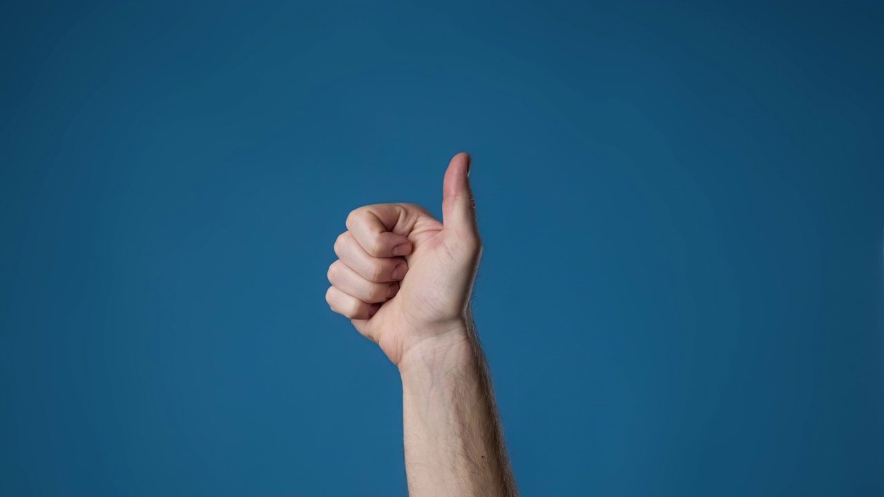 男人的手对着蓝色的背景竖起大拇指。男性的手势像手势。视频下载