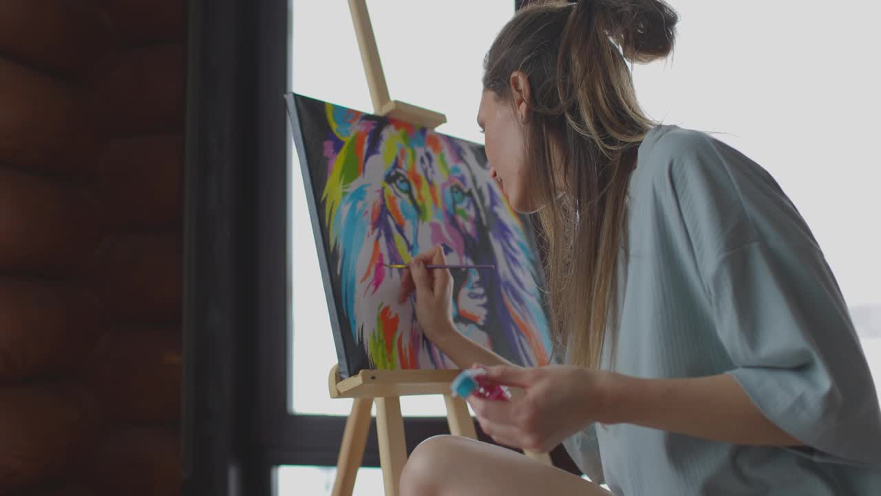 独自在家的业余爱好，女艺术家在木屋窗边的帆布上画画。慢动作视频素材