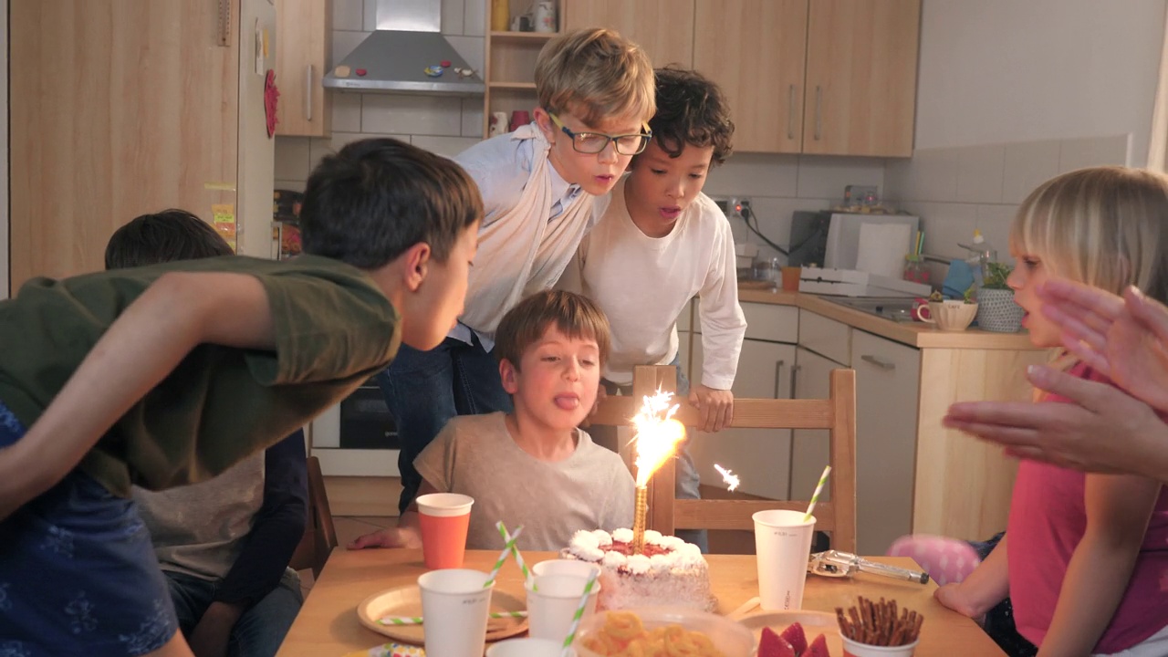 孩子们在生日蛋糕上吹着亮晶晶的烟火蜡烛视频下载