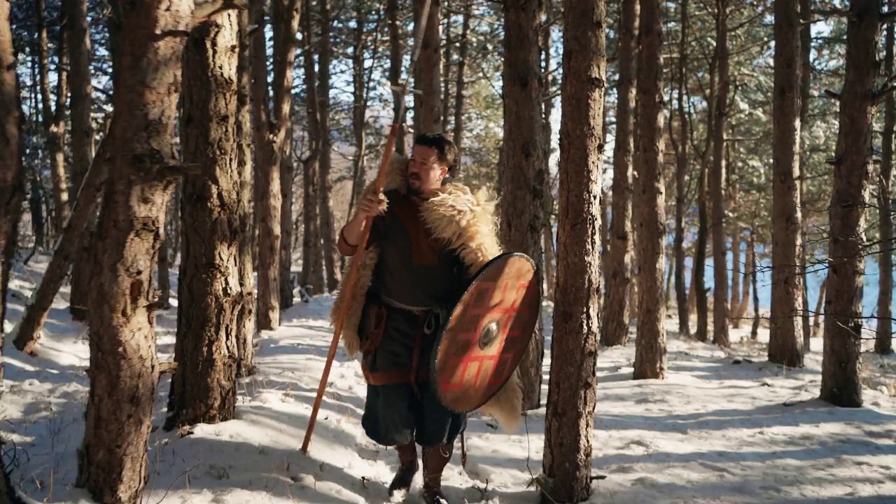 中世纪中期的武士，手持长矛和盾牌，在日落时分穿过森林视频素材