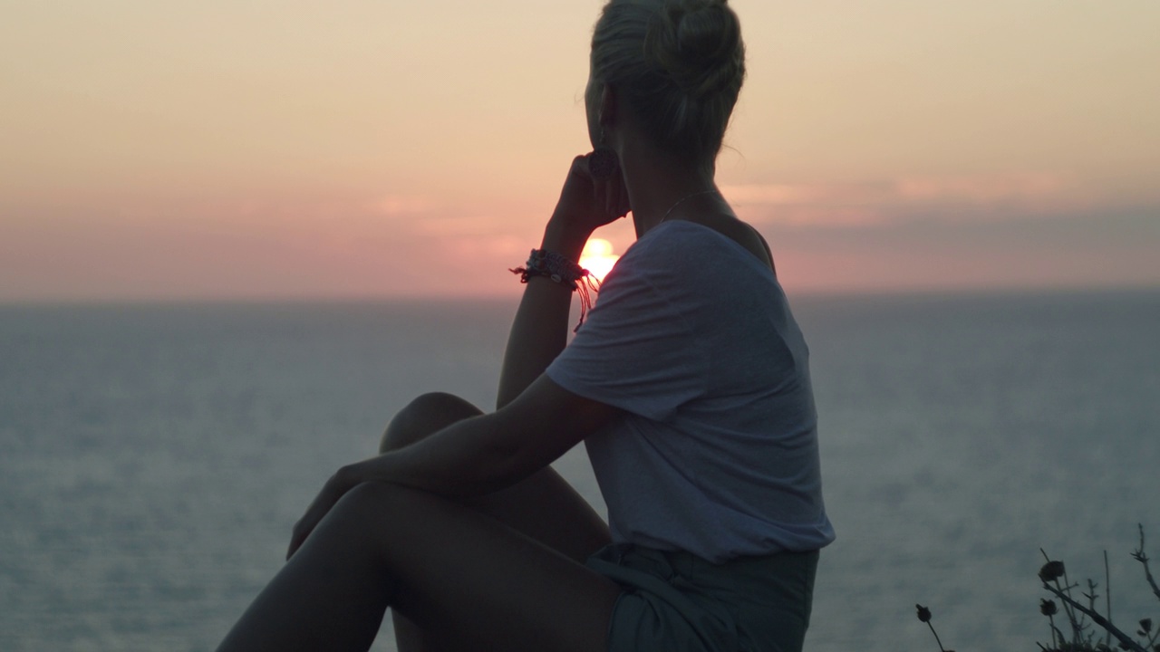 欣赏日落日出的女人。后视图。女孩在海滩上放松。地中海。电影的冥想。视频素材