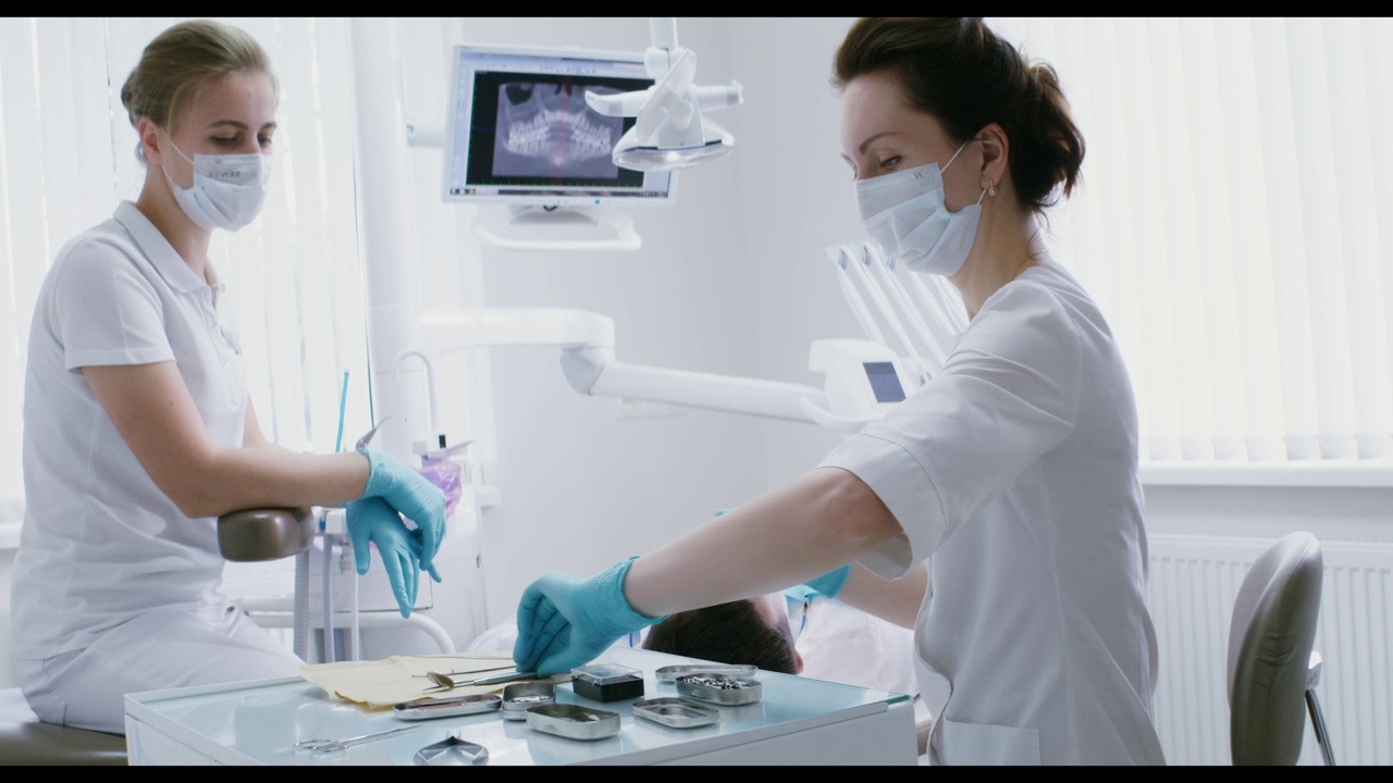 一位女牙医拿着仪器检查病人的口腔视频素材