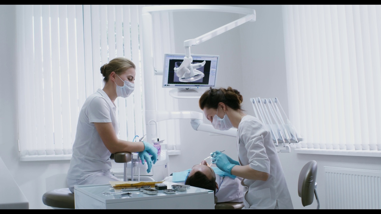 一位女牙医正在检查躺在牙科椅上的病人的口腔视频素材