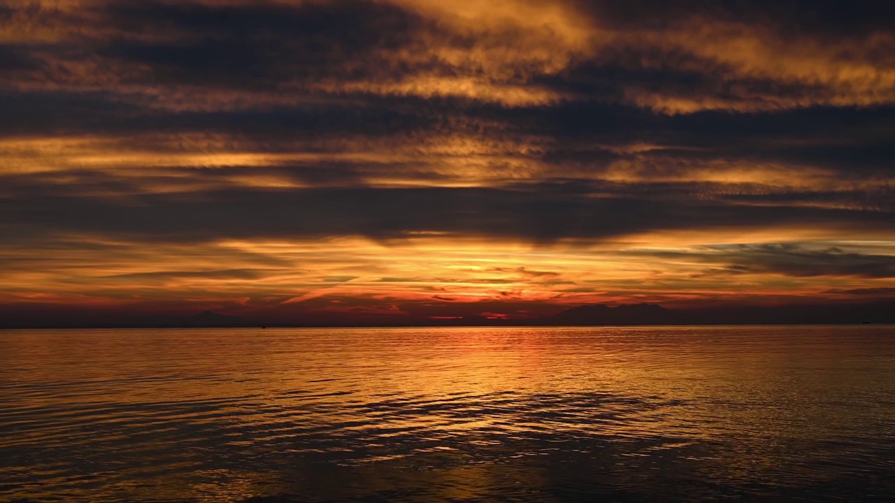 希腊爱琴海上的日落。黄灯，水，陆地在远处视频素材
