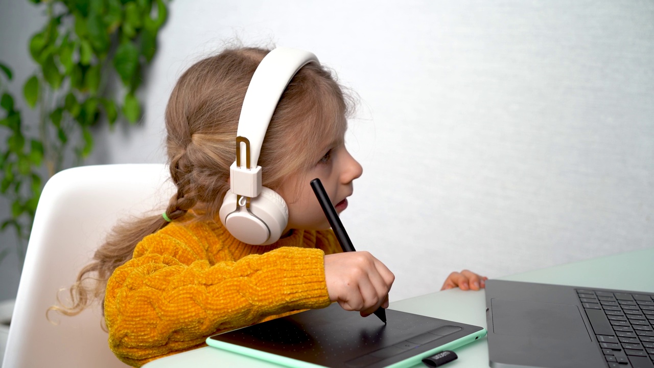 一个小女孩在网上学习图形平板电脑，一个戴耳机的孩子在笔记本电脑上学习图形设计视频下载