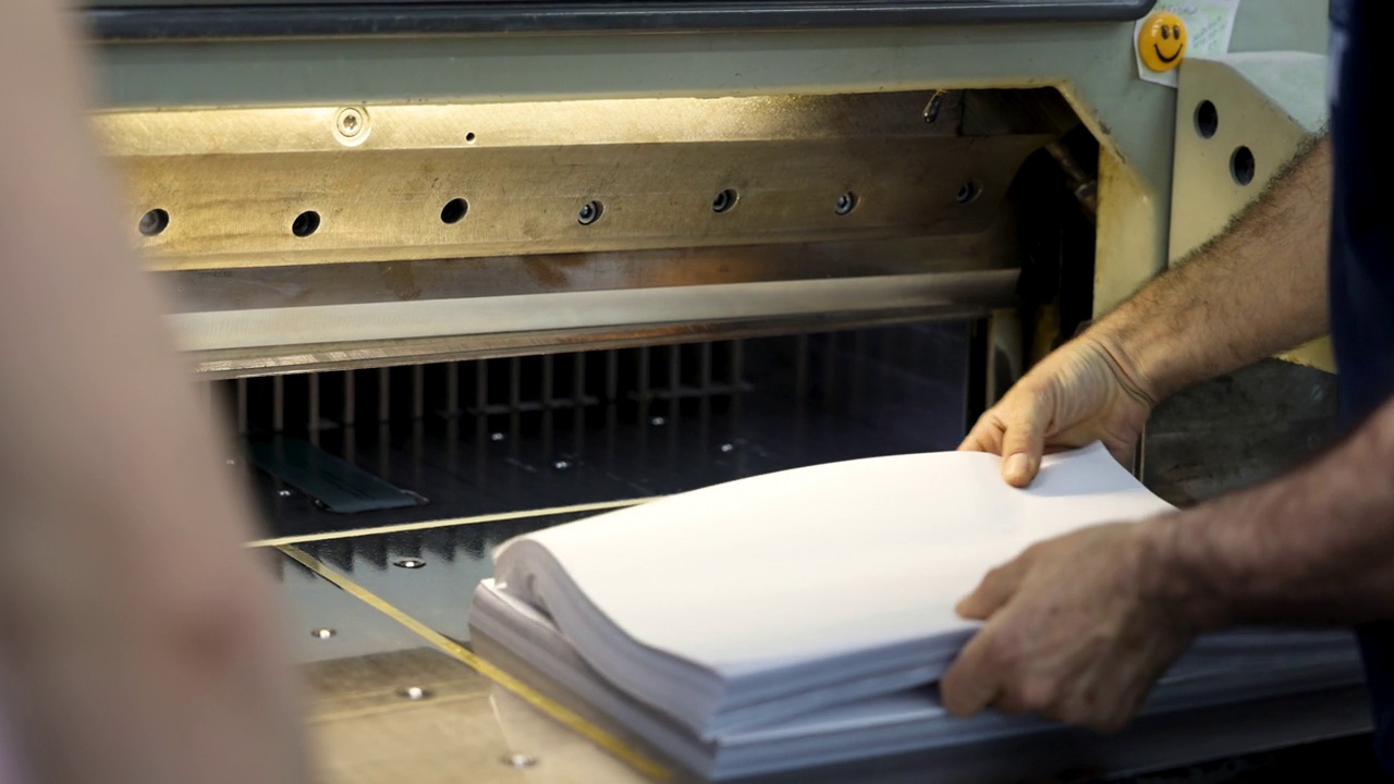 印刷厂的白人工人，在数控切割机上裁纸视频下载
