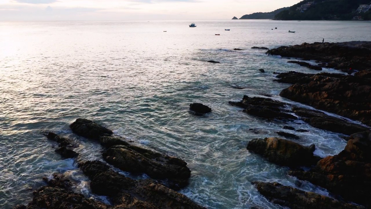 4K无人机俯视图鸟瞰大海蔚蓝的海浪击在岩石和沙滩上。美丽的海水浪来到海滩。泰国普吉岛热带海滩视频素材
