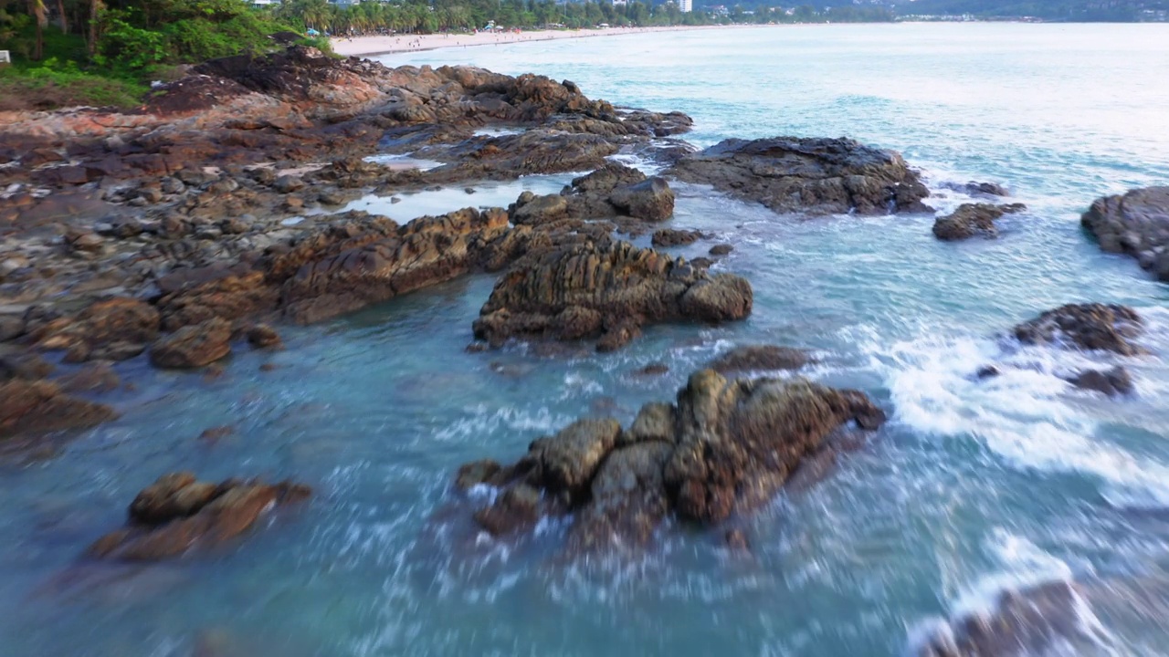 4K无人机俯视图鸟瞰大海蔚蓝的海浪击在岩石和沙滩上。美丽的海水浪来到海滩。泰国普吉岛热带海滩视频素材