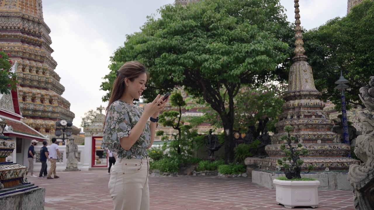 Z世代幸福亚洲女游客在泰国曼谷的Wat Pho / Wat arun寺庙使用数字设备手机直播视频下载