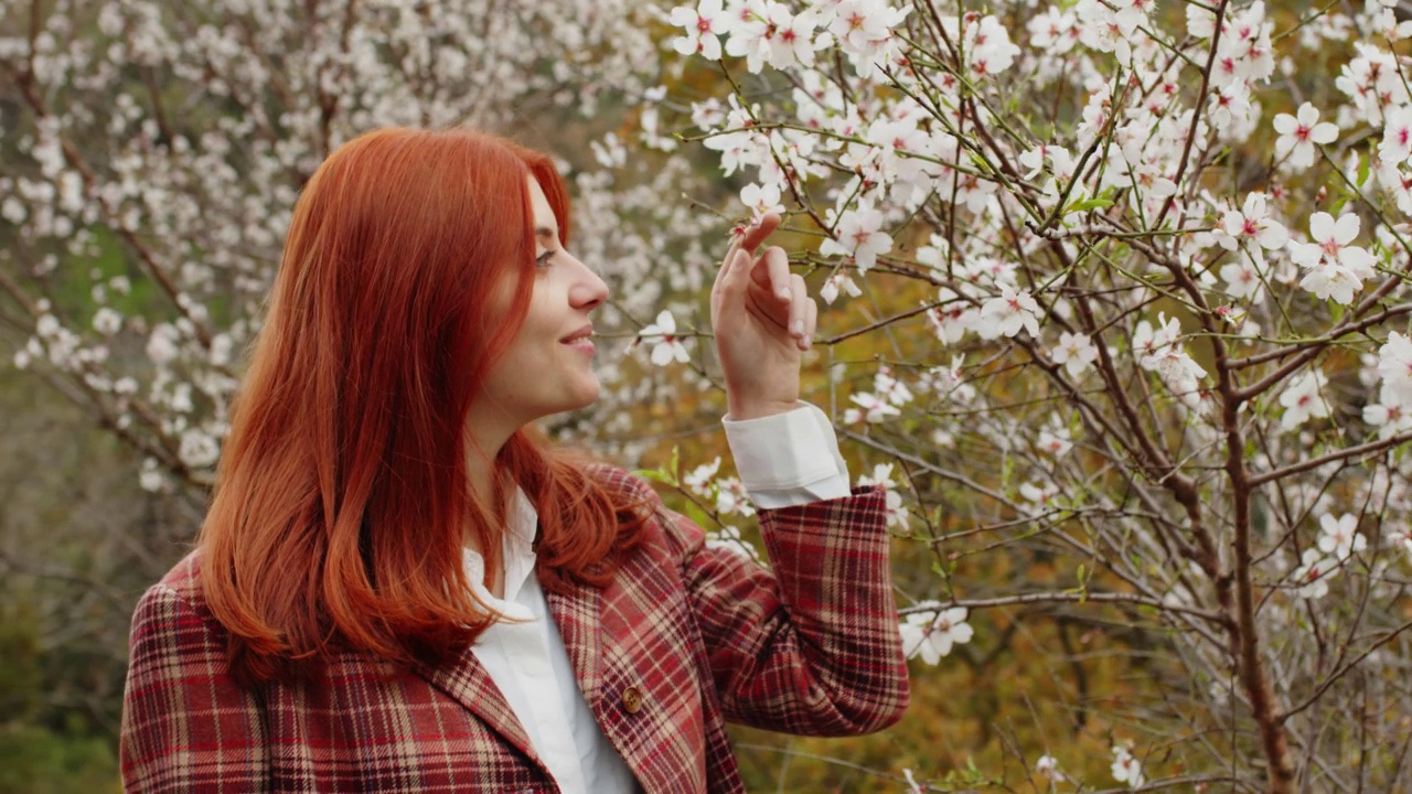 春天花树下快乐的红发女孩。春天的心情。视频下载