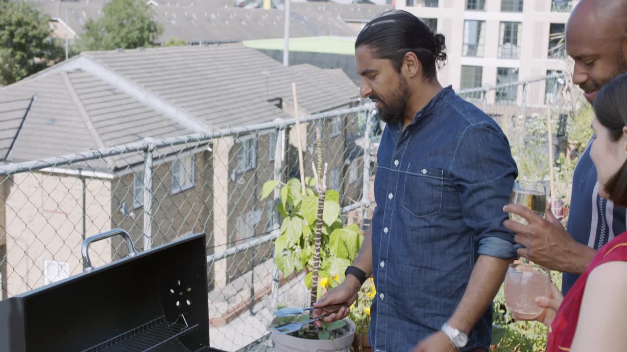 亚洲男人在屋顶露台上烧烤食物和和朋友聊天视频素材