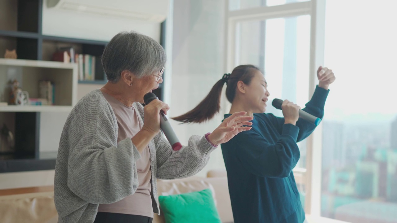 亚裔华人老太太周末与女儿在客厅唱卡拉ok跳舞视频下载