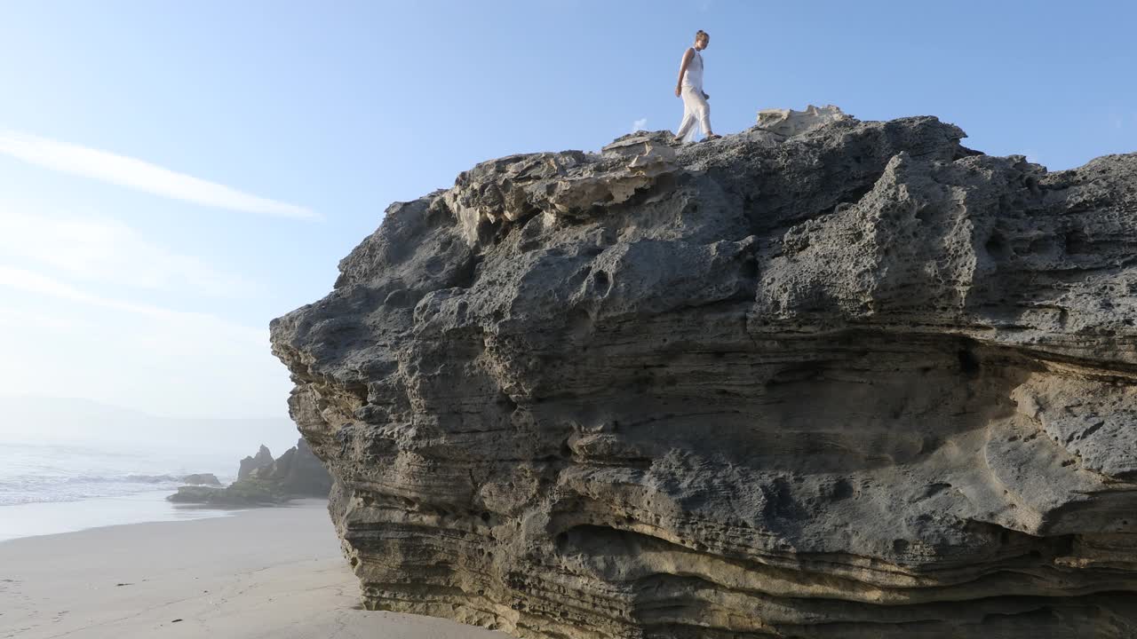 一个十几岁的女孩在沃克湾自然保护区的岩石海岸探险视频素材