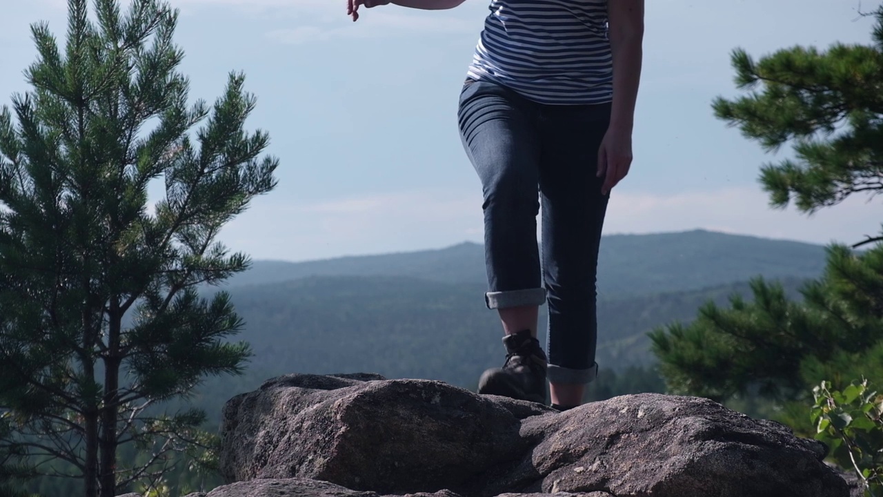 这是一个女性旅行者在夏天穿着登山靴在山顶行走的腿部特写。缓慢的运动。视频素材