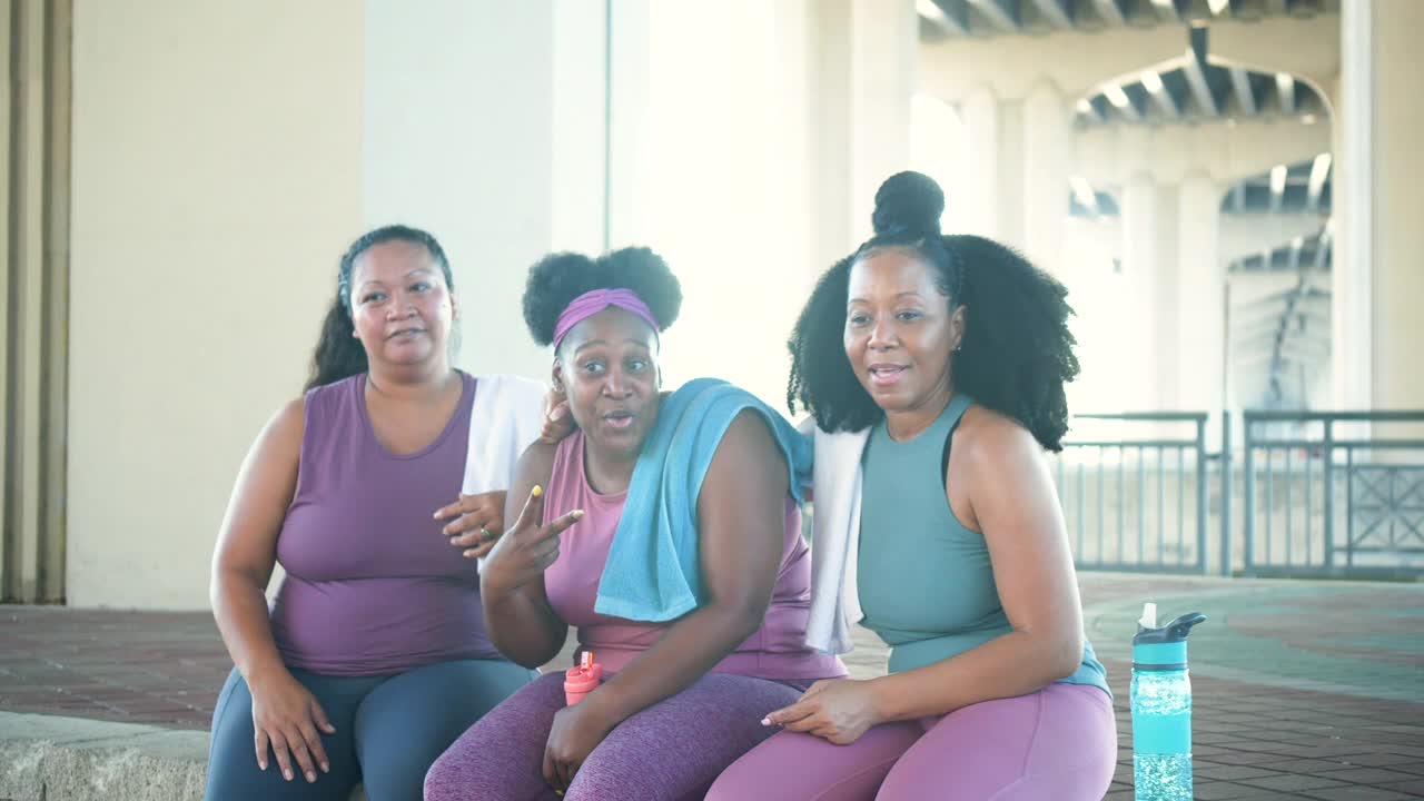 多种族妇女在锻炼后坐在一起，做出和平的手势视频下载