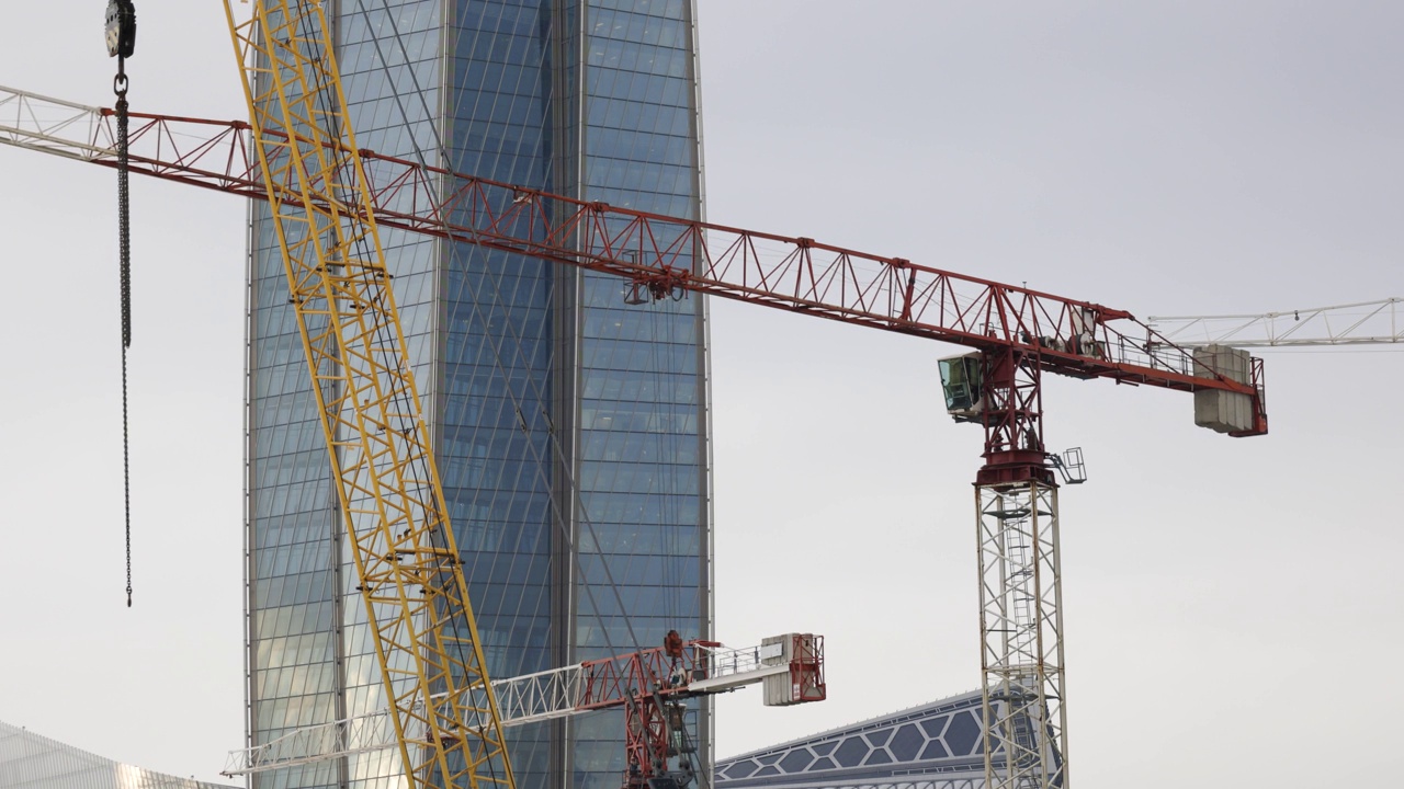 高架起重机在一个玻璃建筑塔的建筑工地上工作视频素材