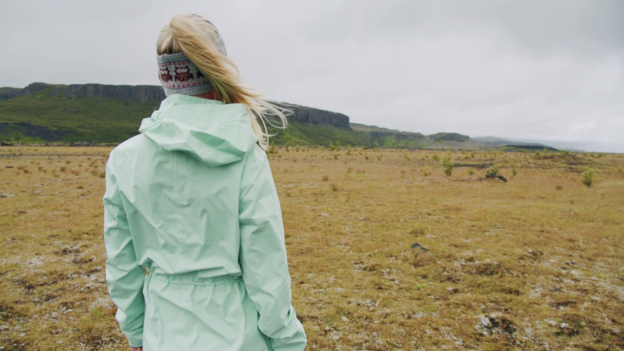 冰岛。年轻迷人的女孩站在户外的火山和山区景观的背景后视镜。视频素材