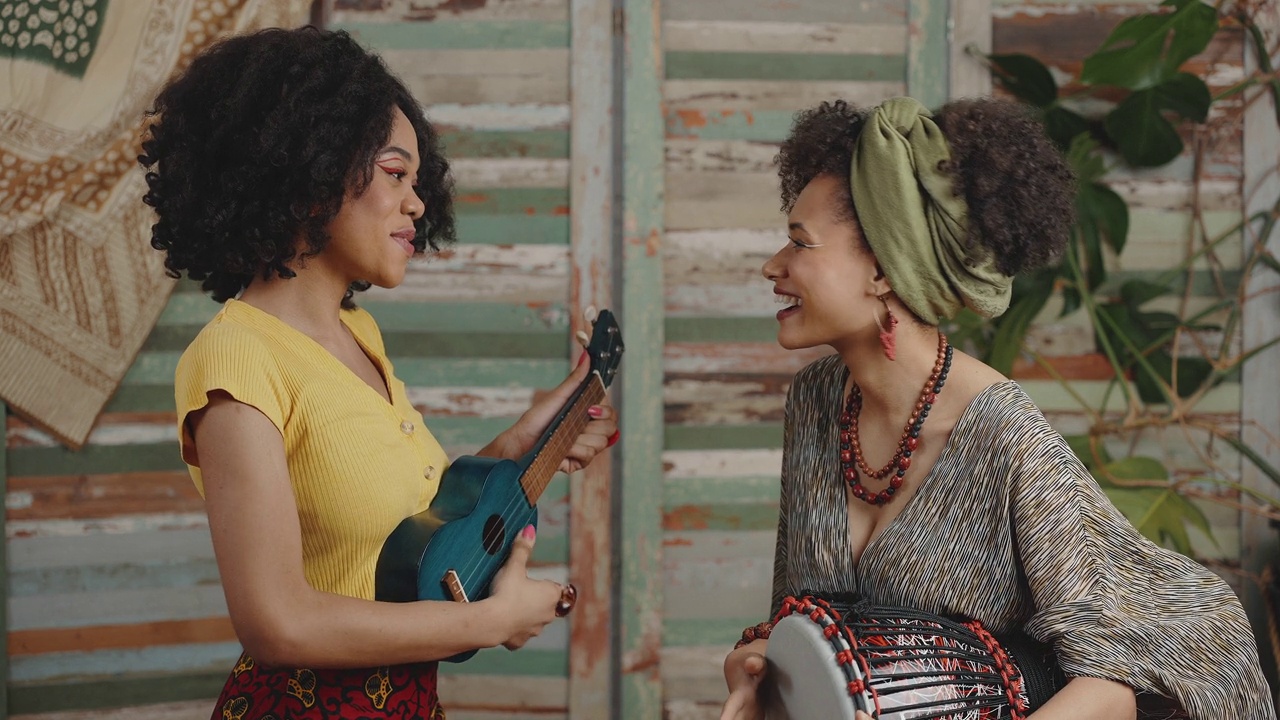传统的非洲音乐。两个年轻的非裔美国女性用尤克里里琴和手鼓演奏音乐视频下载