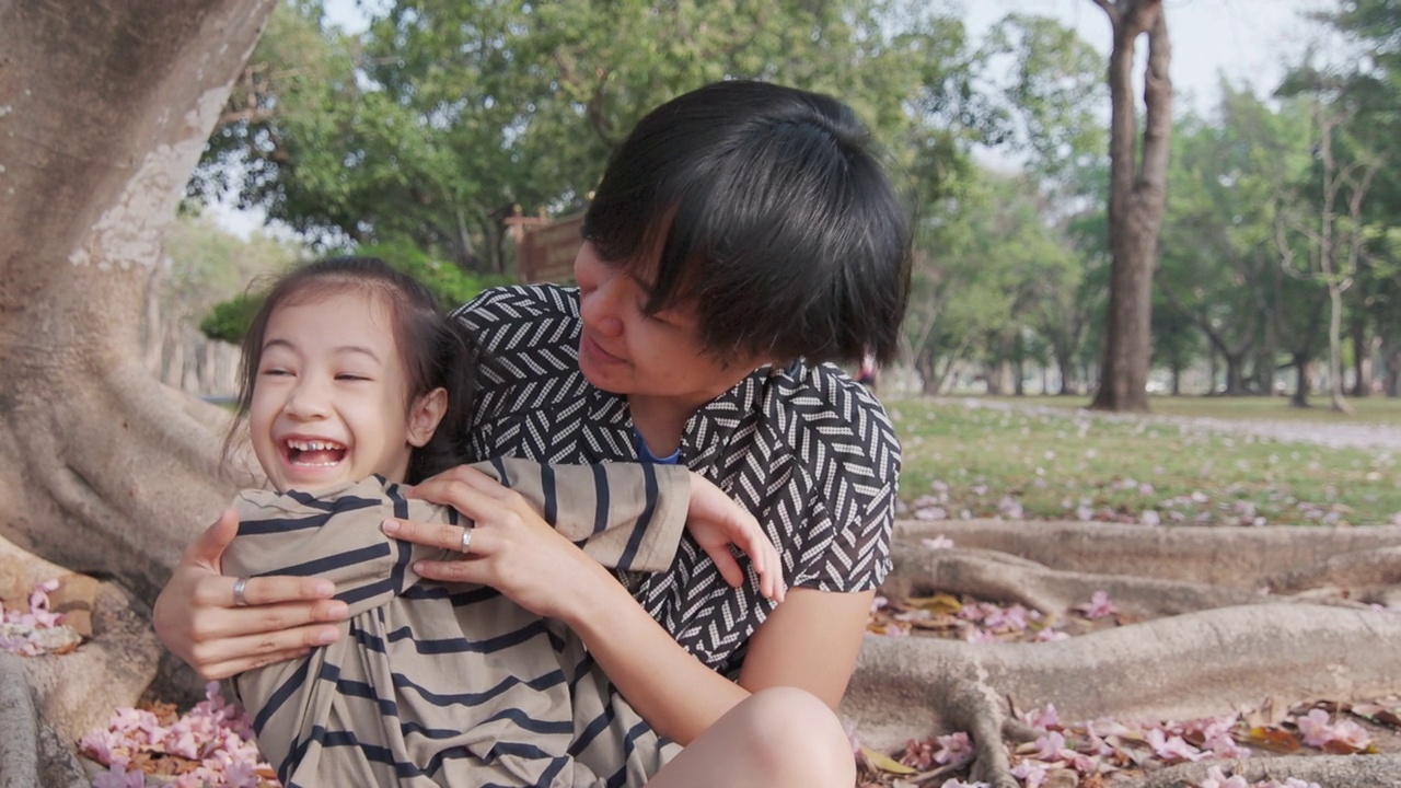 图为，在美丽的公园里，亚洲妈妈和女儿拥抱在一起玩耍。它表达了爱和关心的关系与幸福和快乐，这对孩子是有好处的。视频下载