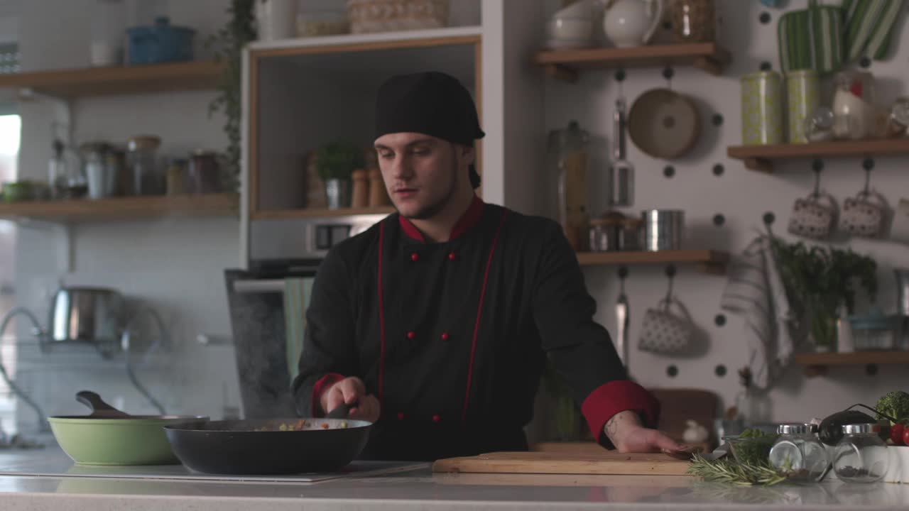 自信的年轻厨师在平底锅里搅拌sautéing蔬菜视频下载