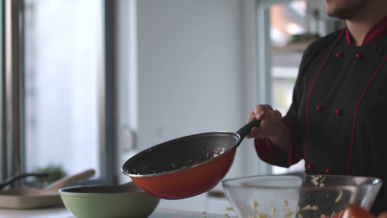 熟练的厨师sautéing西葫芦丁和红洋葱在炉子上方的煎锅视频下载