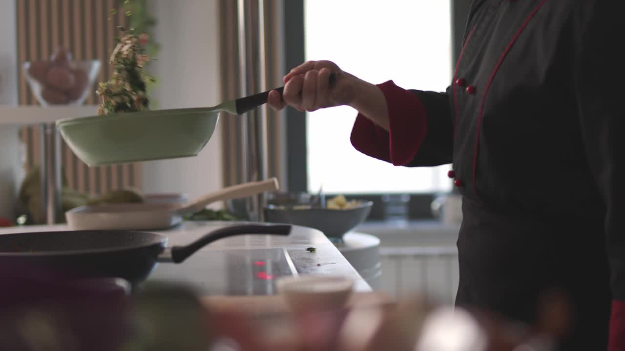 熟练的厨师sautéing把蘑菇和香草放在炉子上的煎锅里视频下载