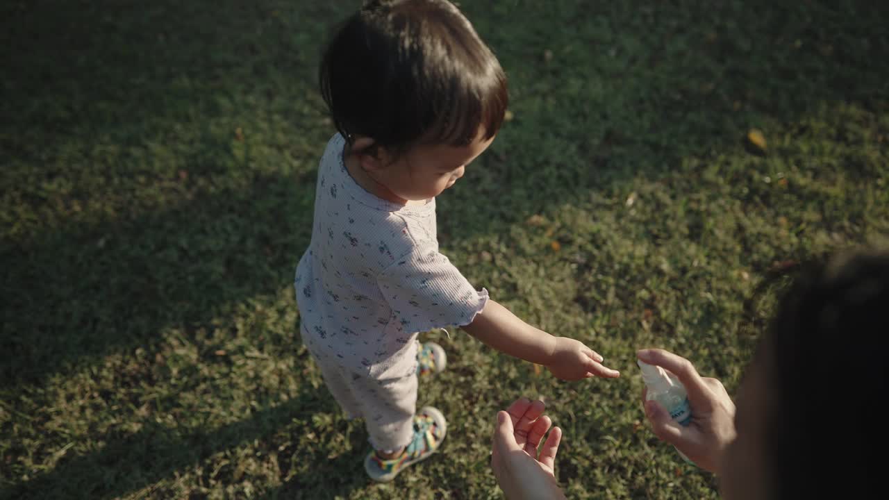 新冠病毒传播期间，亚洲母亲教女儿用酒精喷雾洗手液洗手视频下载