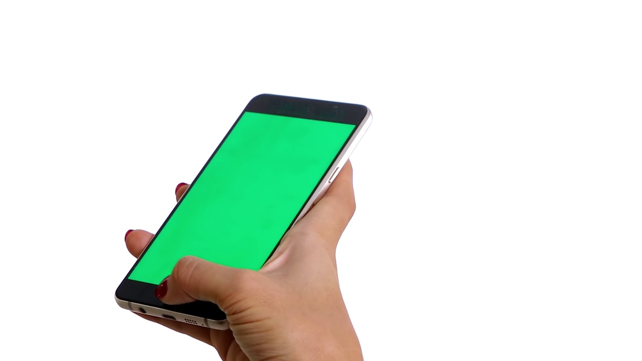 视频片段显示，一位女性的手在使用一部绿色屏幕的智能手机，孤立在白色背景上。拍摄分辨率为4k视频素材