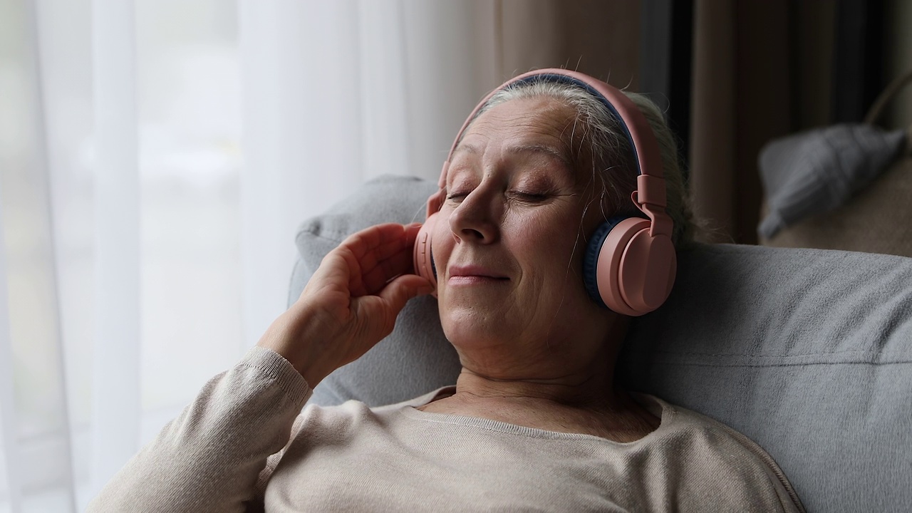 上了年纪的女人喜欢高质量的声音，戴上耳机听喜欢的音乐视频下载