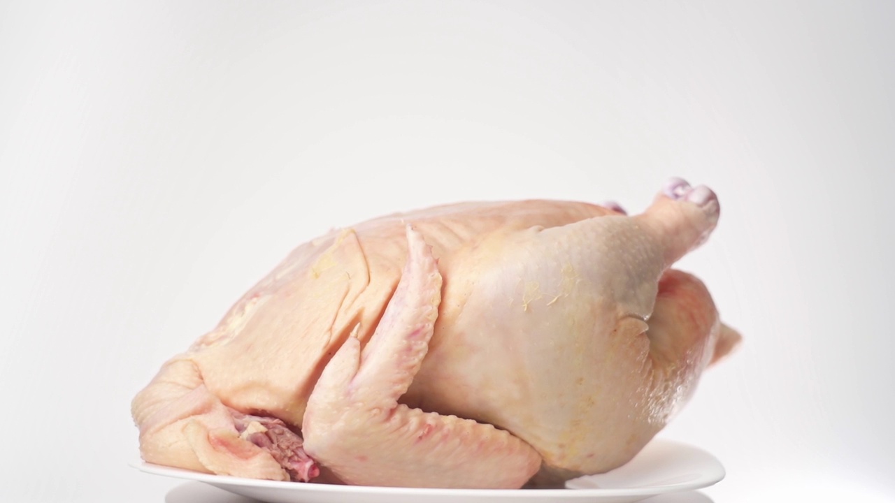 鸡的尸体躺在一个浅盘上，在白色背景上旋转视频下载