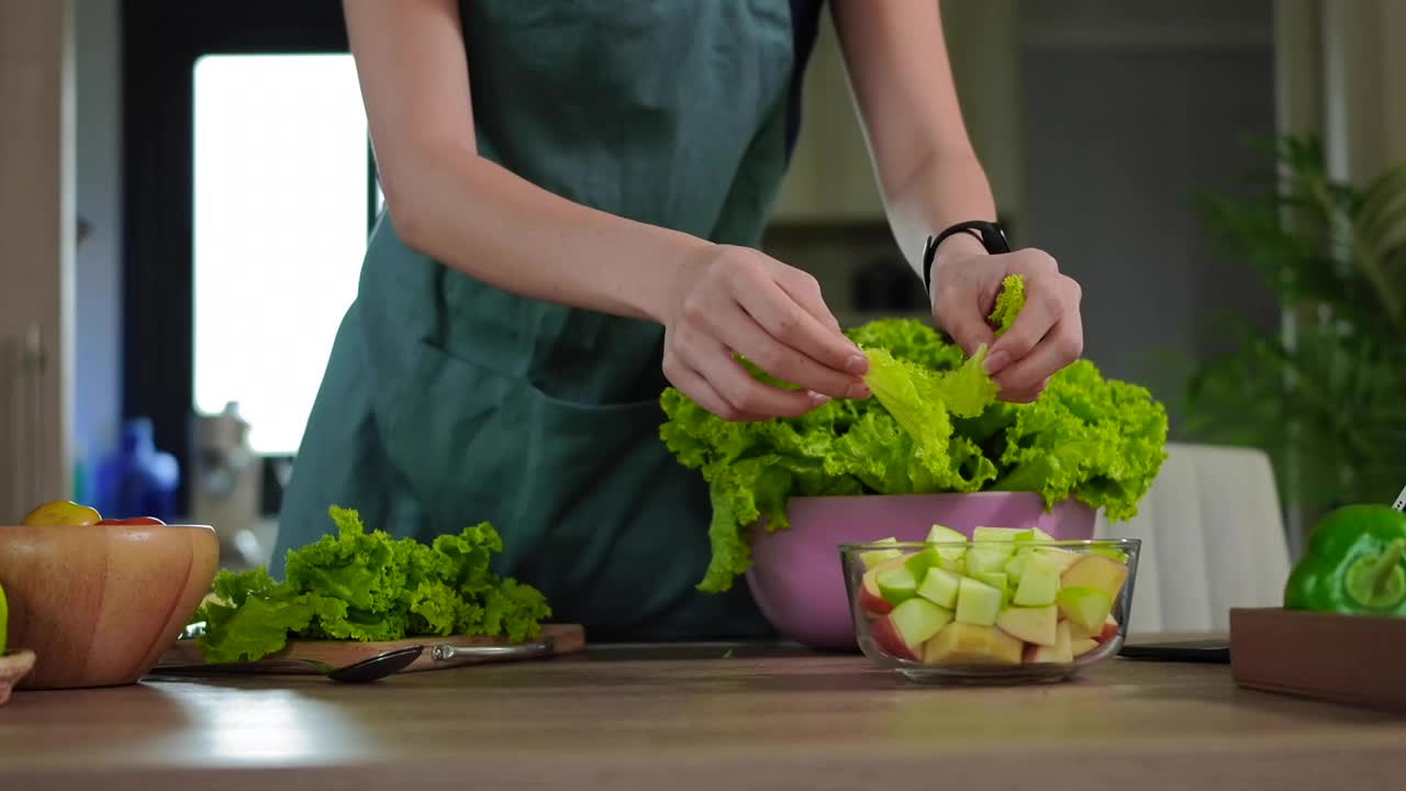 年轻女子在厨房为素食准备水果和蔬菜。视频素材