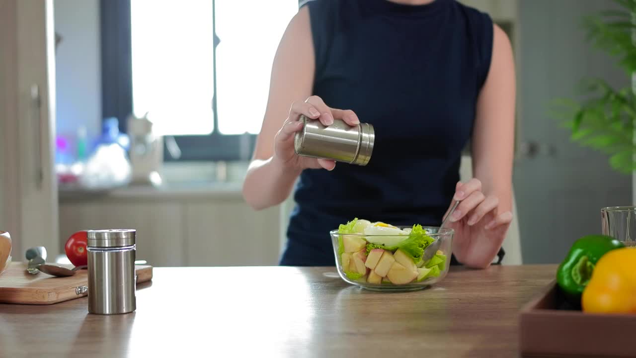 女人的手倒盐和混合沙拉在一个玻璃碗。健康的生活方式。视频素材