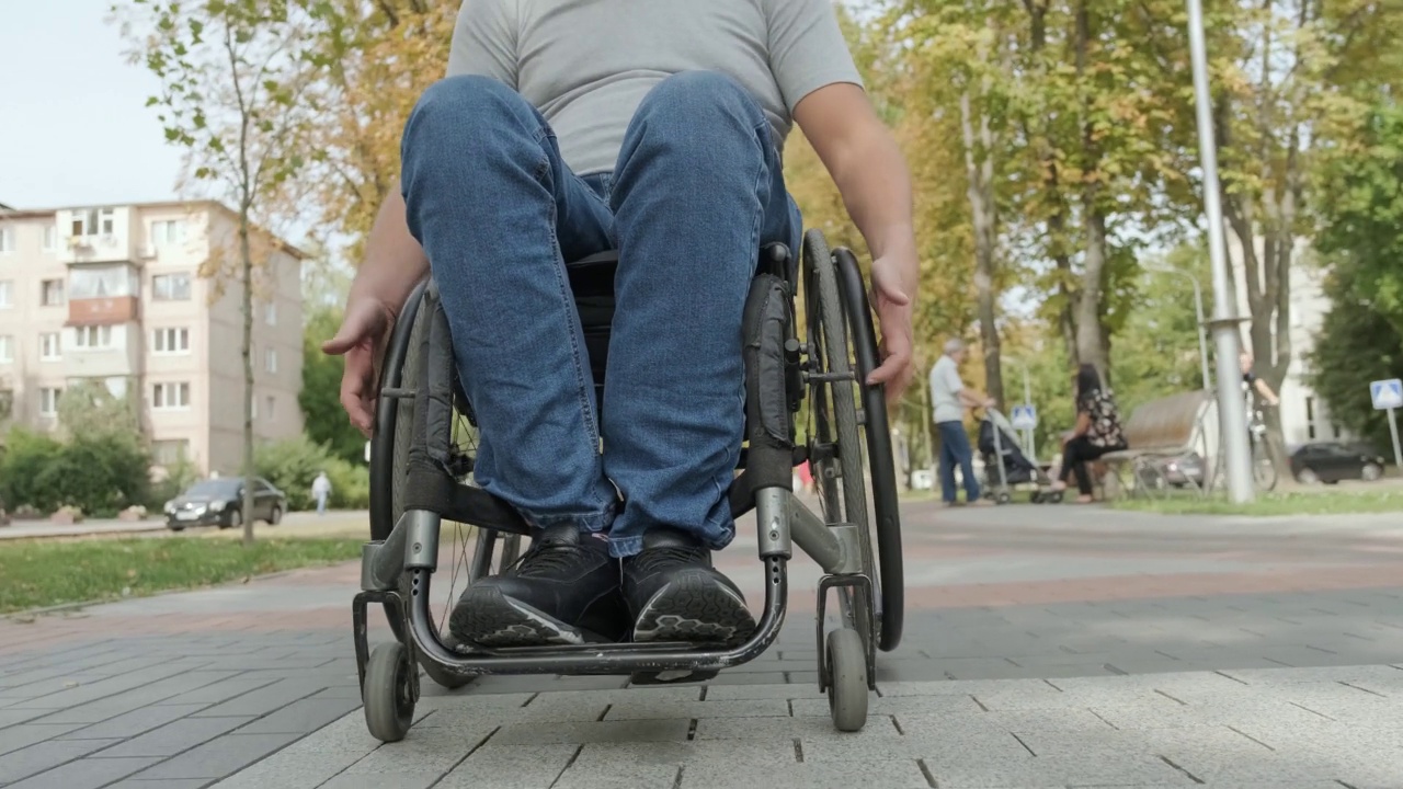 一个坐轮椅的残疾人走在公园的小路上视频下载