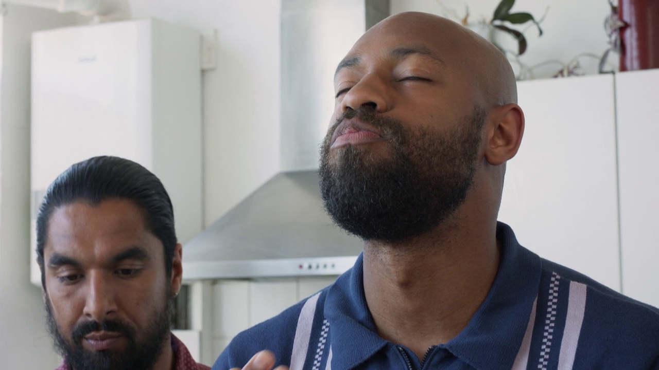 留着胡子的中年黑人男子和一位亚洲朋友在品尝食物，脸上带着满意的表情视频下载