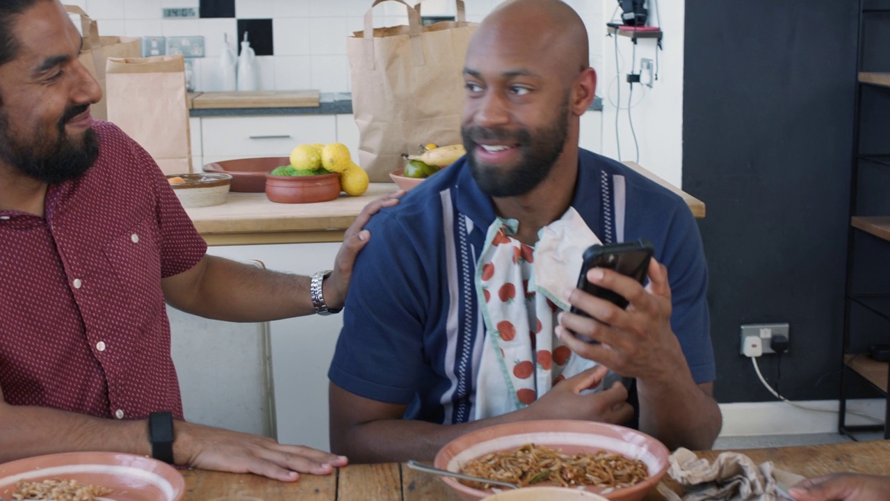 黑人和朋友在餐桌上用手机，然后把手机收起来视频下载
