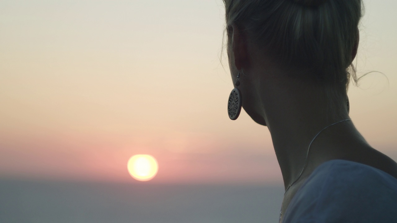 近距离拍摄美丽的金发女人看在海上日落。视频素材