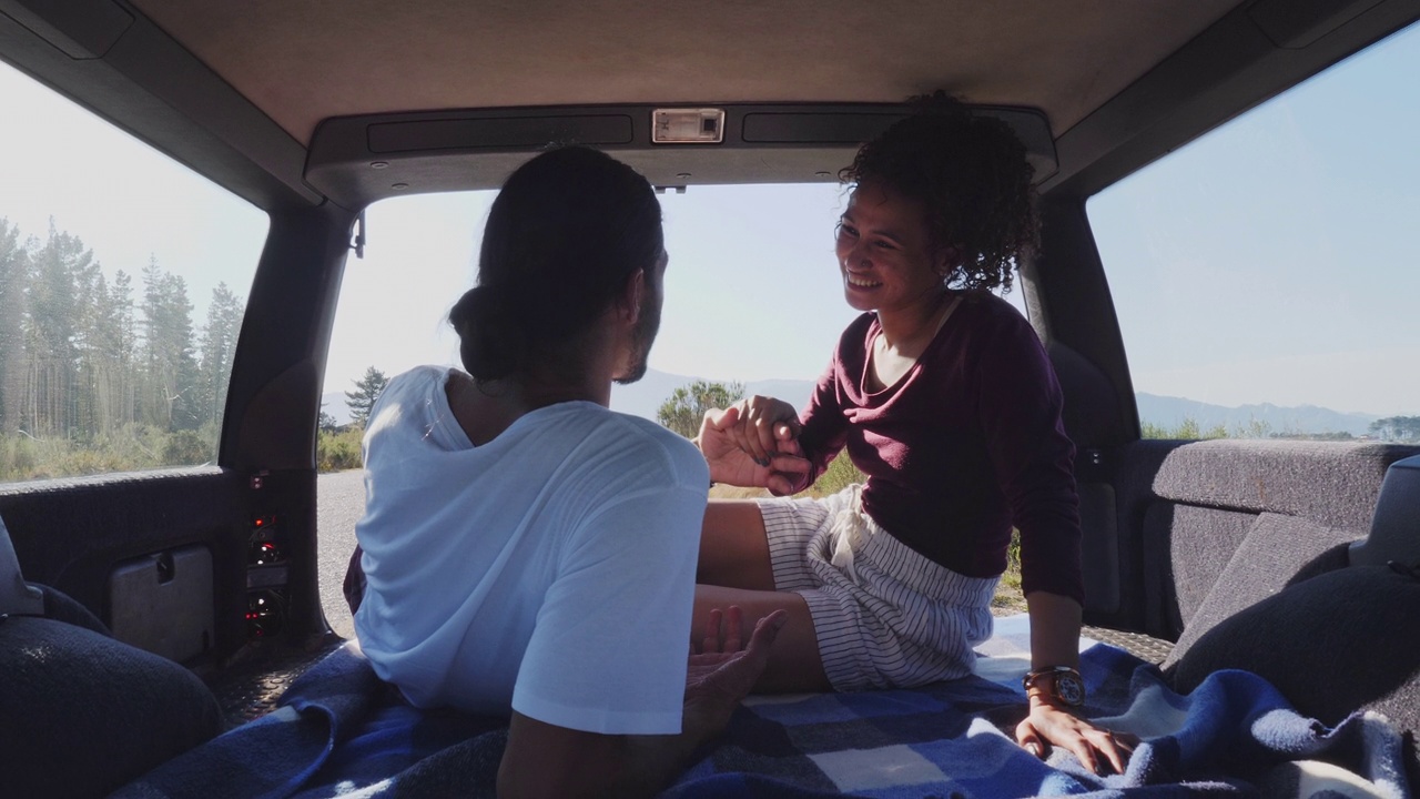 一对年轻夫妇在阳光明媚的汽车后座聊天视频下载