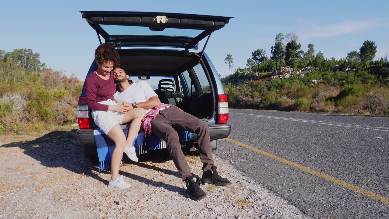 一对深情的年轻夫妇在阳光明媚的路边的车后放松视频下载