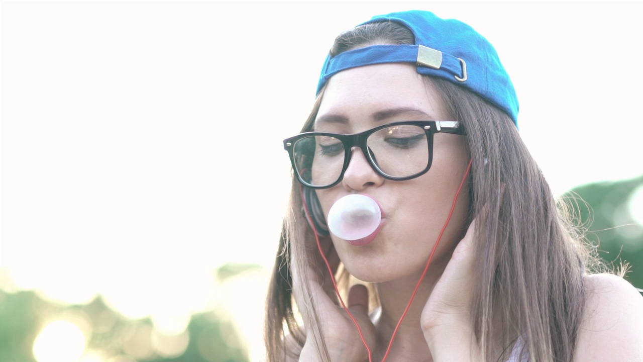 年轻的都市女子在吹泡泡糖视频素材