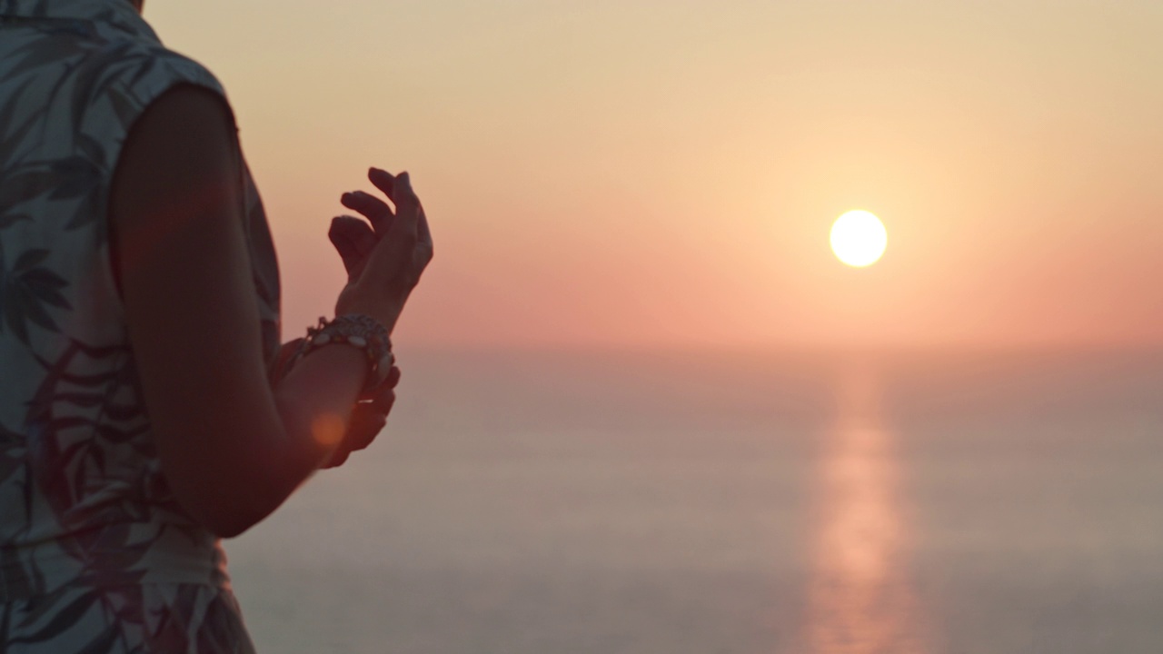 女人的手和落日的火红的太阳球在地平线上。暑假假期概念视频素材