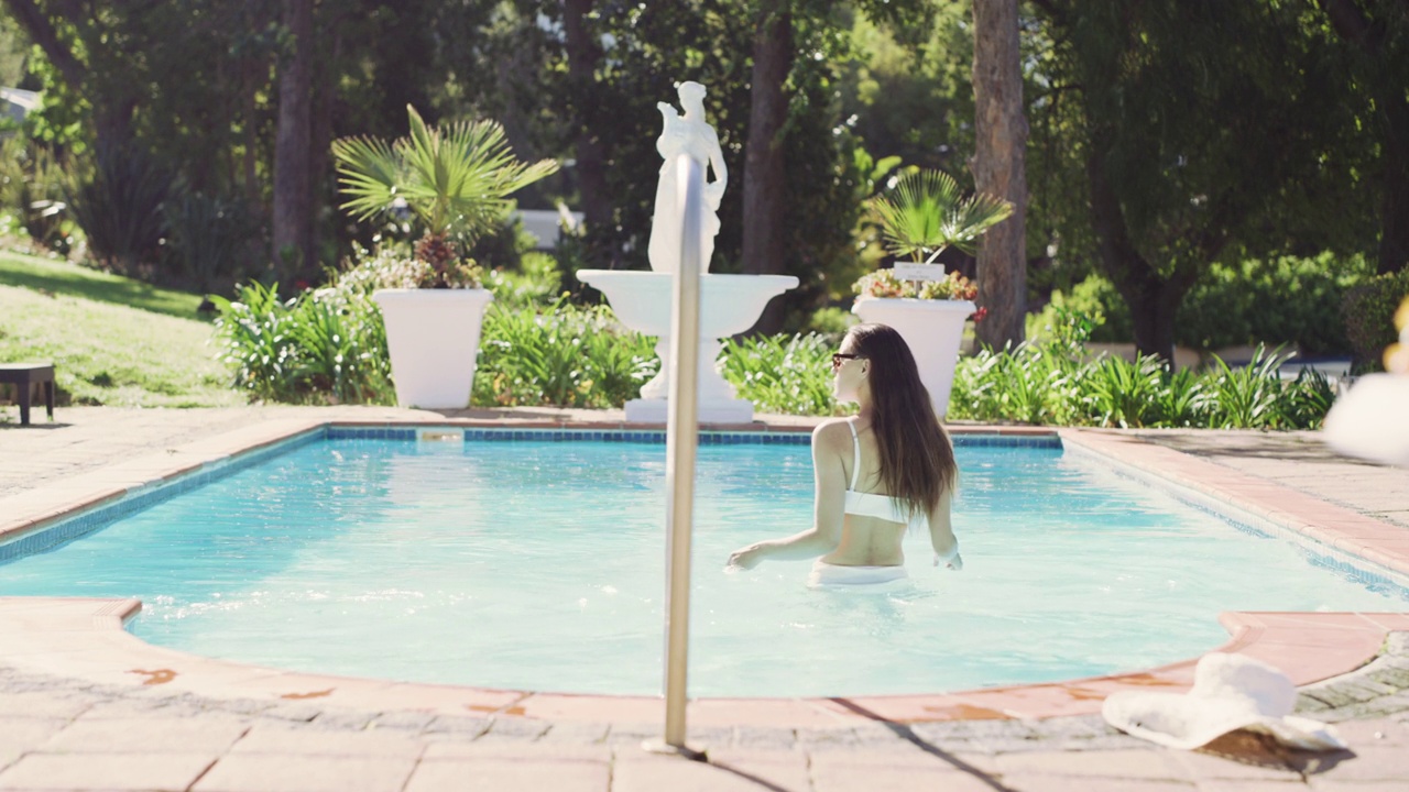一个迷人的年轻女子在度假时准备在游泳池游泳的4k视频片段视频素材