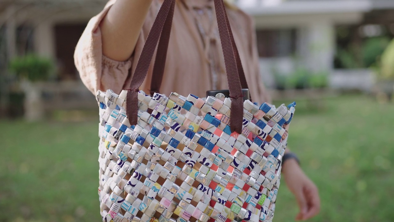 一名亚洲妇女将回收塑料产品放入一个可循环使用的环保塑料袋中视频下载