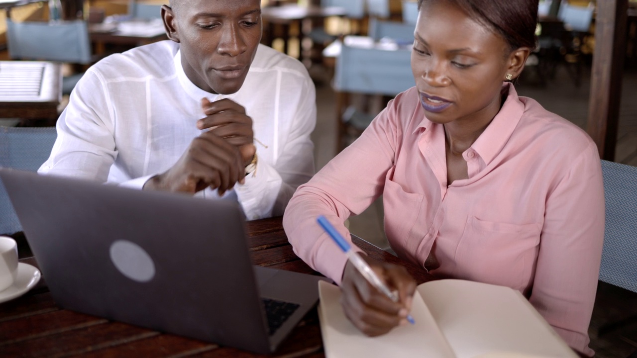 黑人同事一边用笔记本电脑工作，一边聊天，计划café。视频下载