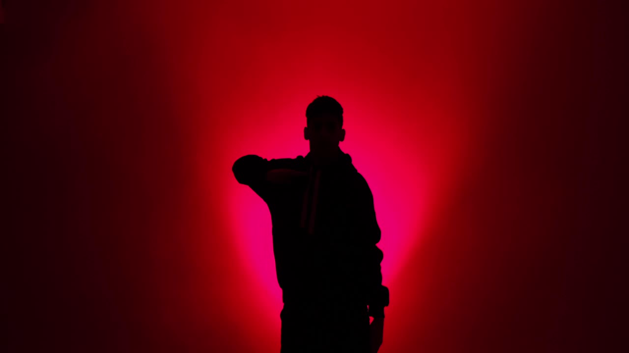 一个年轻人在红灯下跳嘻哈舞的剪影视频素材