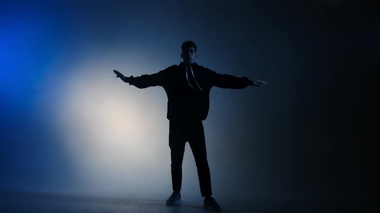 一个年轻人在蓝色的灯光下跳着嘻哈舞视频素材